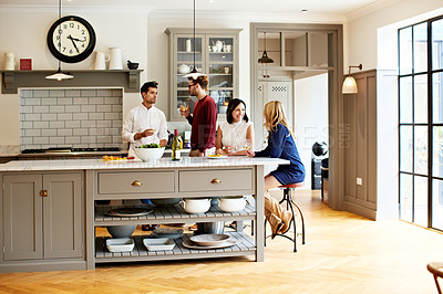 Buy stock photo Shot of a group of friends talking and drinking wine while preparing a meal together