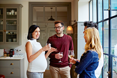 Buy stock photo Shot of a group of friends drinking wine and talking together in a kitchen at a get-together