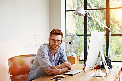 Buy stock photo Portrait of a smiling young man sitting at a desk in his home office
