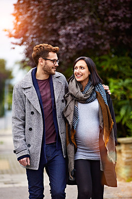 Buy stock photo Shot of a young pregnant woman and her husband enjoying a walk together