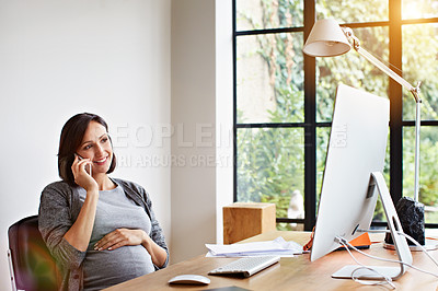 Buy stock photo Shot of a pregnant woman talking on the phone while sitting at a desk in her home office