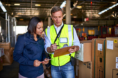 Buy stock photo Shot of two warehouse workers using a digital tablet and looking at paperwork