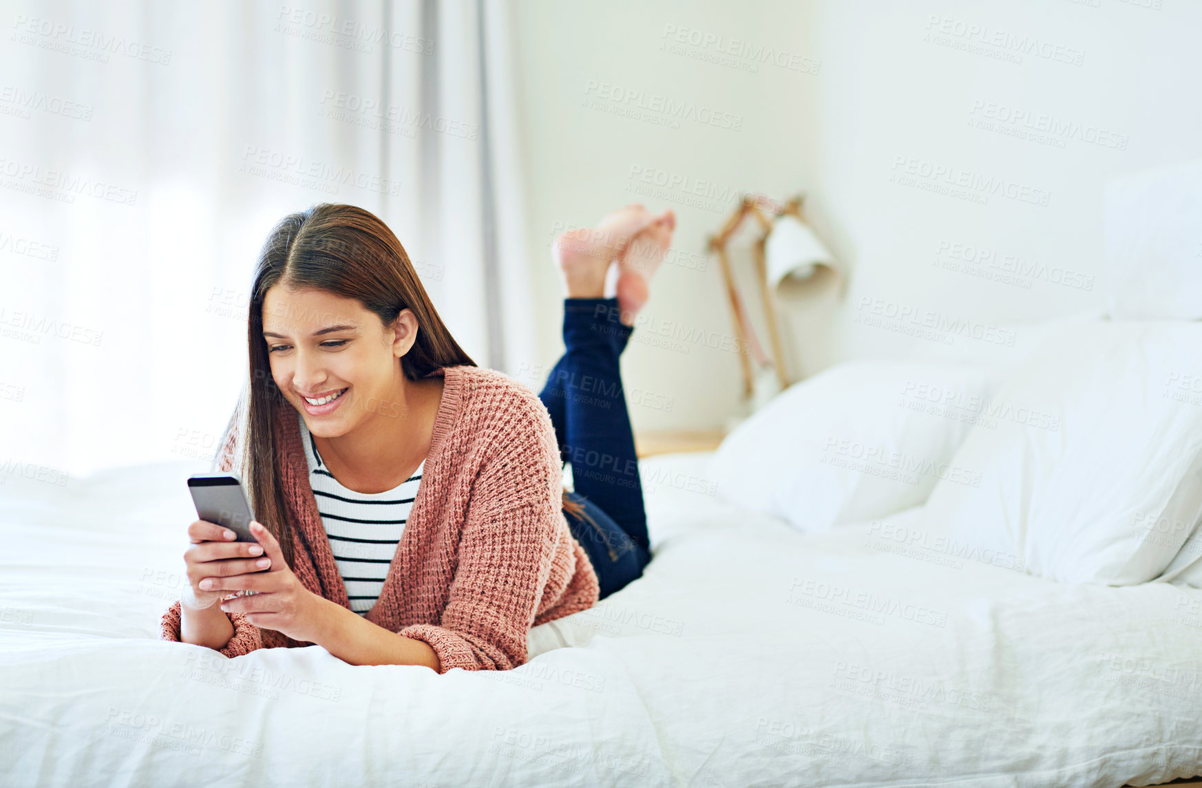Buy stock photo Phone, relax and happy woman in bedroom for internet communication, download or gaming app. Smile, social media and female person with mobile on bed at home, morning and play game on weekend break
