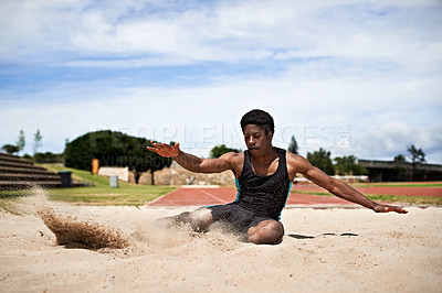 Buy stock photo Shot of a young woman landing in sand after a long jump