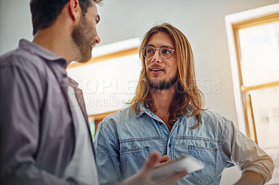 Buy stock photo Shot of two colleagues talking together while standing in an office