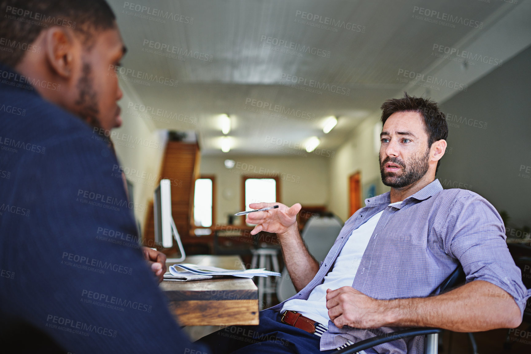 Buy stock photo Shot of two colleagues in deep discussion together while sitting at a desk in an office