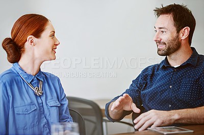 Buy stock photo Shot of two smiling colleagues talking together in an office