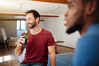 Buy stock photo Shot of colleagues talking and drinking beers together while winding down after work