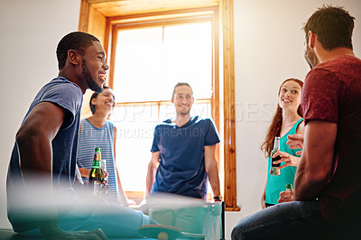Buy stock photo Shot of a group of colleagues talking and drinking beers together while winding down after work