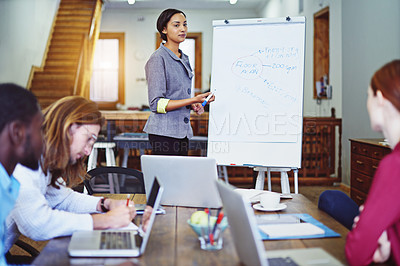 Buy stock photo Shot of a young woman giving a whiteboard presentation to colleagues in an office