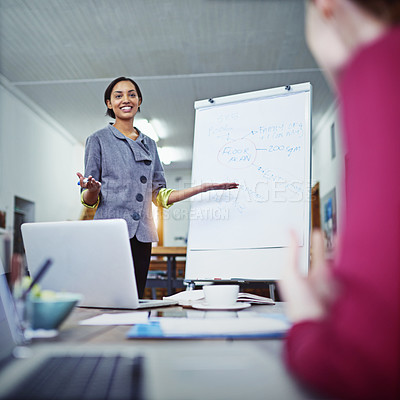 Buy stock photo Shot of a young woman giving a whiteboard presentation to colleagues in an office