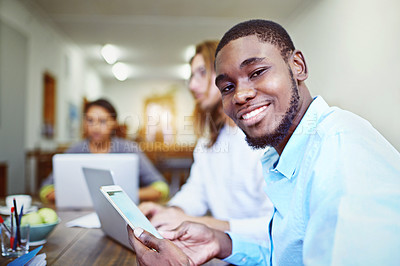 Buy stock photo Portrait of a young man sitting in an office using a digital tablet with colleagues in the background