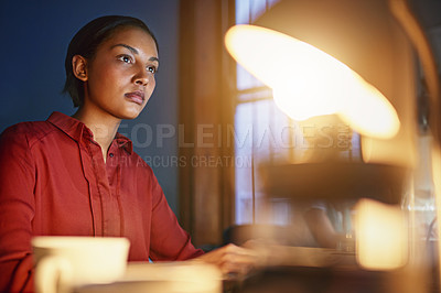 Buy stock photo Shot of a young woman working at her desk in an office in the evening