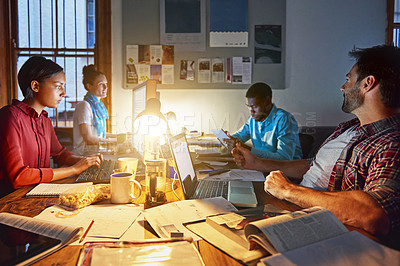 Buy stock photo Shot of a group of designers at work around a table in the evening