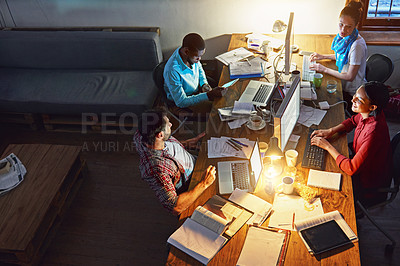 Buy stock photo High angle shot of a group of designers at work around a table in an office in the evening
