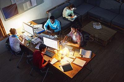 Buy stock photo High angle shot of a group of designers at work around a table in an office in the evening
