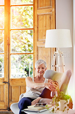 Buy stock photo Portrait of a smiling mature woman relaxing on a chair at home with a glass of wine