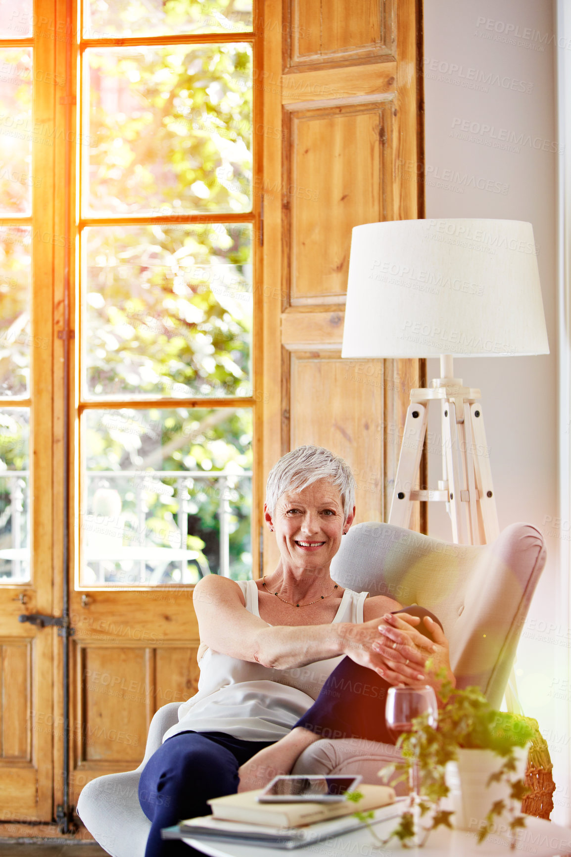 Buy stock photo Portrait of a smiling mature woman relaxing on a chair at home with a glass of wine