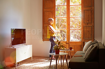 Buy stock photo Shot of a mature woman standing by a window at home deep in thought