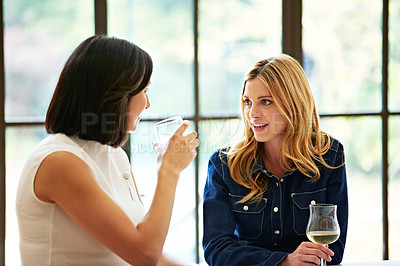 Buy stock photo Shot of two friends talking together while sitting at a dining table at home