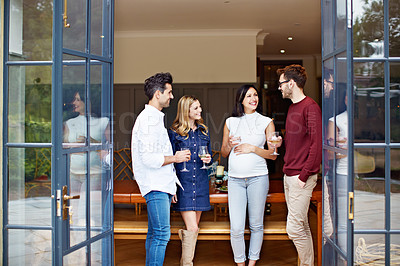 Buy stock photo Shot of a group of friends drinking wine and talking together at a get-together