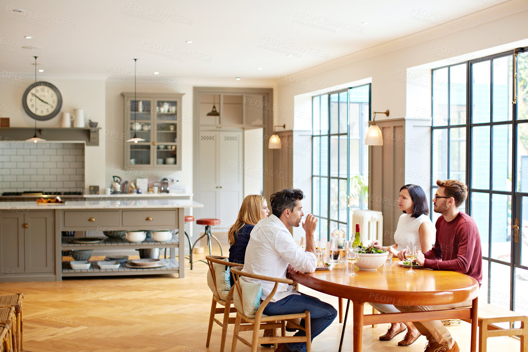 Buy stock photo Talking, home and couple of friends at table for lunch, dinner and social gathering with meal. Happy, house and people with food, wine and conversation for bonding, connection and reunion for visit