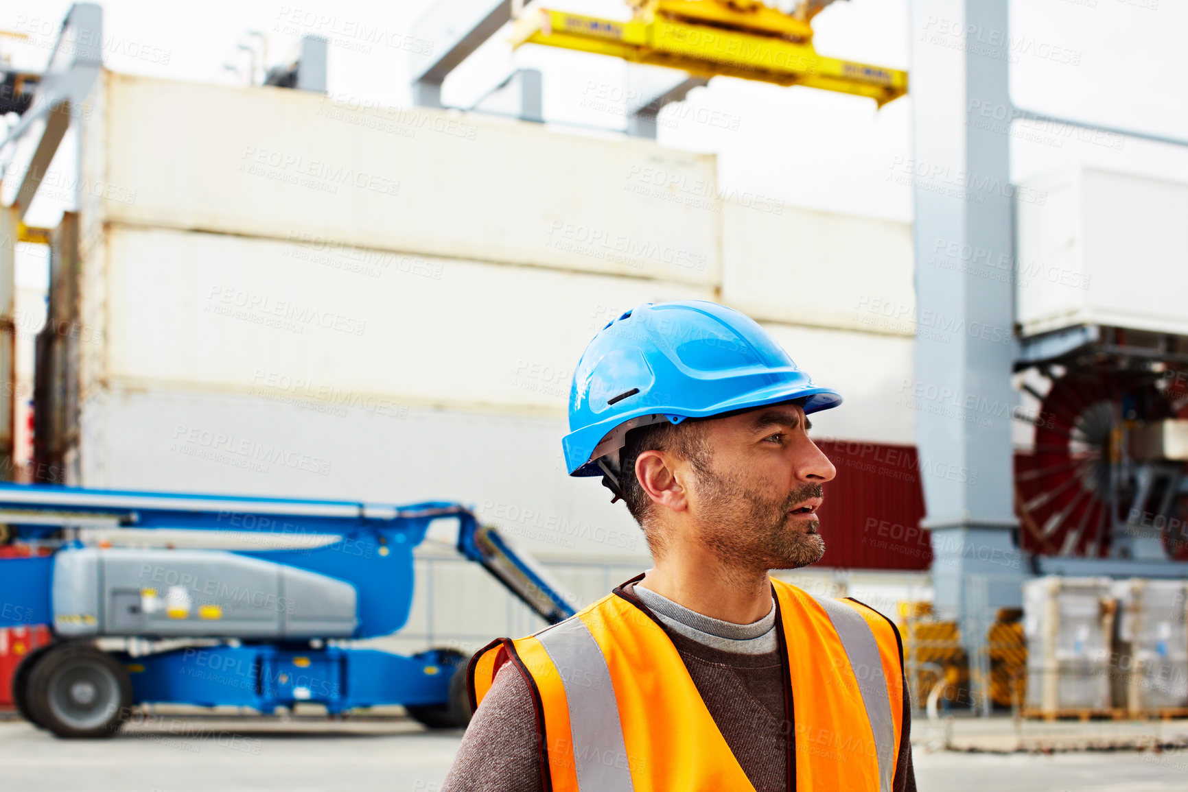 Buy stock photo Shot of a young man in workwear standing outside on a large commercial dock