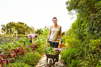Buy stock photo Portrait of a woman pushing a wheelbarrow through her organic garden