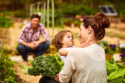 Buy stock photo Shot of a couple and their baby girl working in their organic garden