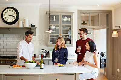 Buy stock photo Shot of a group of friends talking and drinking wine while preparing a meal together