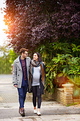 Buy stock photo Shot of a young pregnant woman and her husband enjoying a walk together