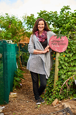 Buy stock photo Portrait of a mature woman standing outside leaning on a community garden sign