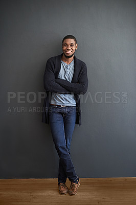 Buy stock photo Portrait of a smiling young man standing with his arms crossed against a gray wall