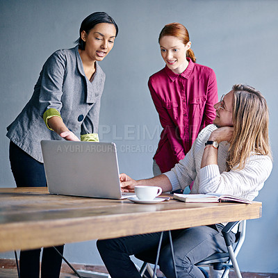 Buy stock photo Shot of a group of colleagues talking together over a laptop on a desk in an office