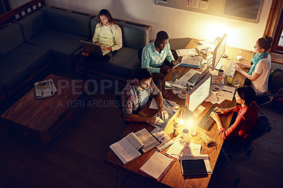 Buy stock photo High angle shot of a group of designers at work around a table in an office in the evening