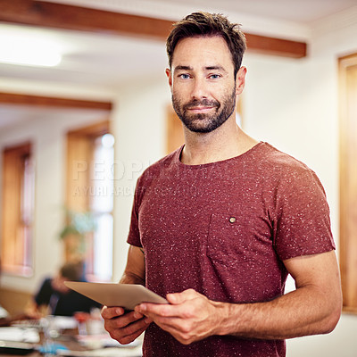 Buy stock photo Portrait of a man standing in an office using a digital tablet with colleagues in the background