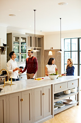 Buy stock photo Shot of a group of friends talking and drinking wine while preparing a meal together