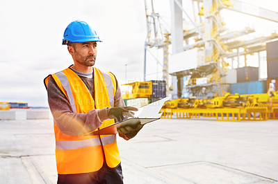 Buy stock photo Shot of a young man in workwear with a clipboard 
standing outside on a large commercial dock