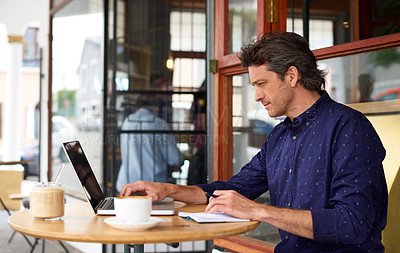 Buy stock photo Shot of a man working on a laptop at a sidewalk table outside of a cafe