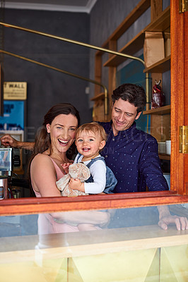 Buy stock photo Portrait of smiling couple and their little girl looking through the window of their cafe