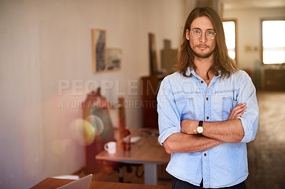 Buy stock photo Portrait of a focused young designer standing with his arms crossed in an office