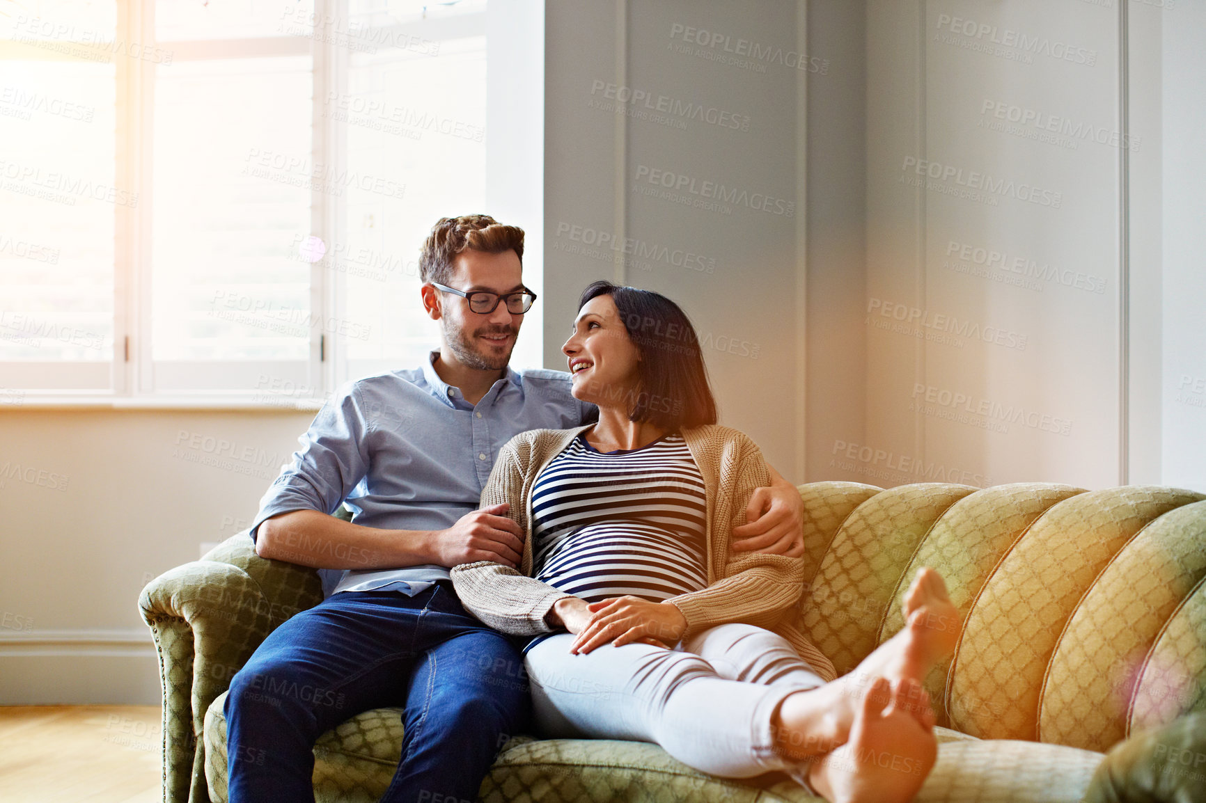 Buy stock photo Shot of an affectionate young couple relaxing on the sofa at home