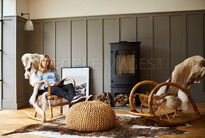 Buy stock photo Shot of a young woman using a digital tablet while relaxing on a rocking chair at home