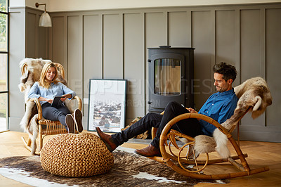 Buy stock photo Shot of a couple using digital tablets while relaxing on rocking chairs at home