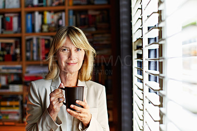 Buy stock photo Portrait of a mature businesswoman drinking coffee while standing at a window in her home