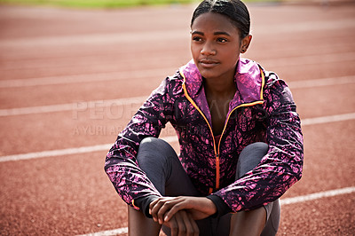 Buy stock photo Shot of an athletic young woman sitting out on the track