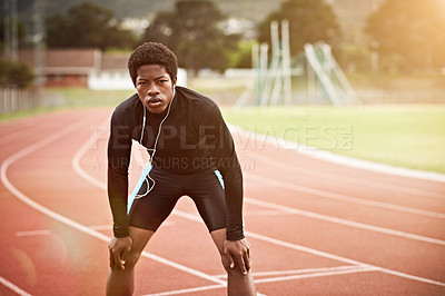 Buy stock photo Cropped shot of a young athlete listening to music while out on the track