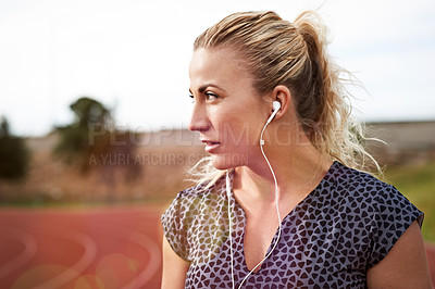 Buy stock photo Cropped shot of a young athlete listening to music while out on the track