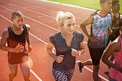 Buy stock photo Shot of a group of young athletes out running on the track