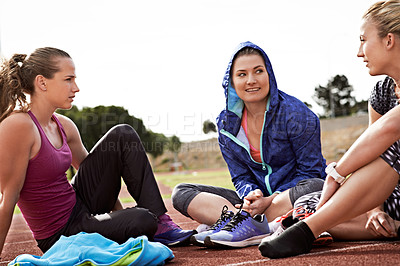 Buy stock photo Shot of a group of young athletes sitting out on the track after a run